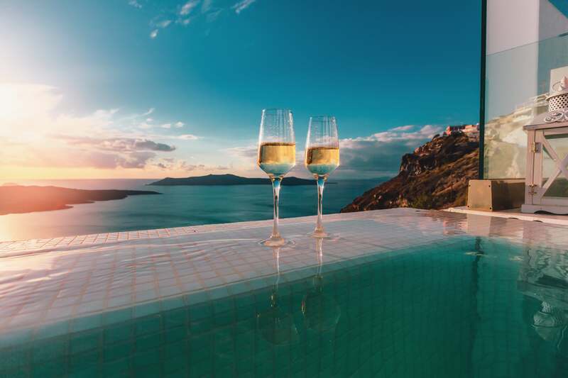 champagne in infiinty pool with view of greek islands