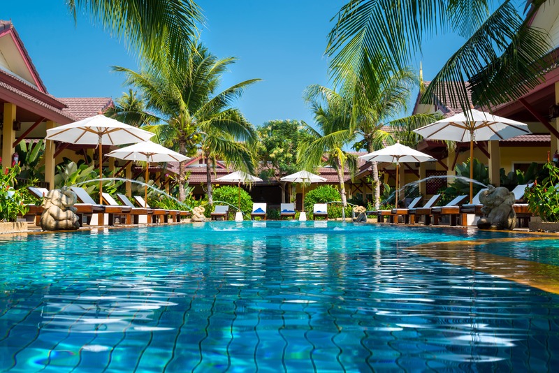 resort pool with lounges, umbrellas and palm trees